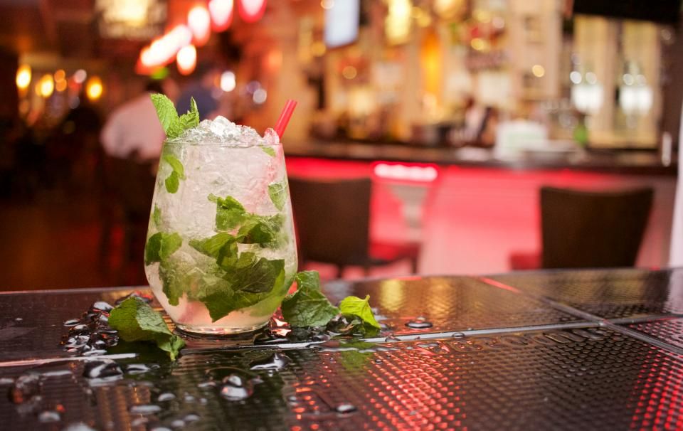 A mint cocktail on the bar with warm lights behind
