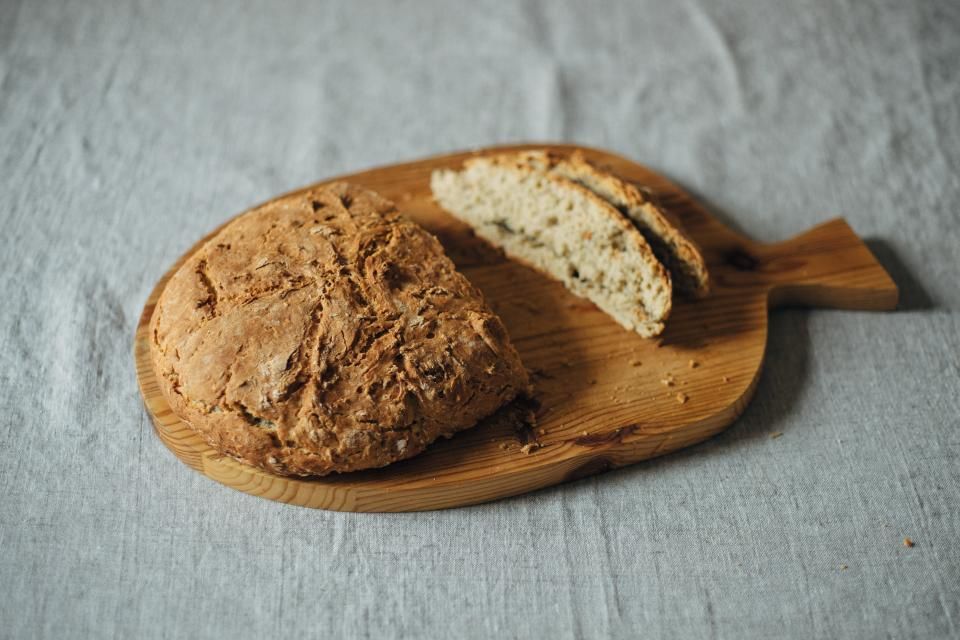 A round loaf, one slice cut, on a wooden board