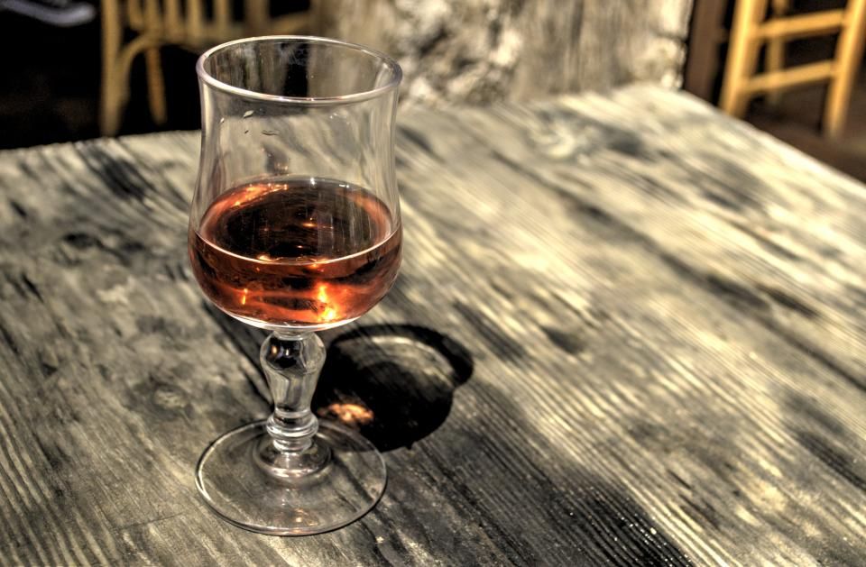A glass of red wine on a worn wooden table